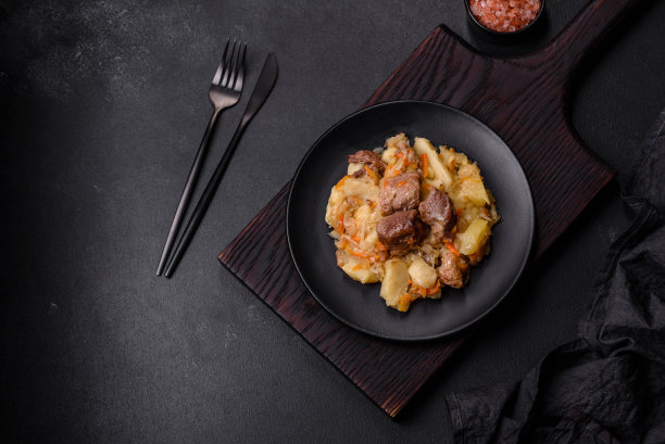 美味的蔬菜炖牛肉，土豆，胡萝卜和卷心菜在一个黑色的盘子里图片下载