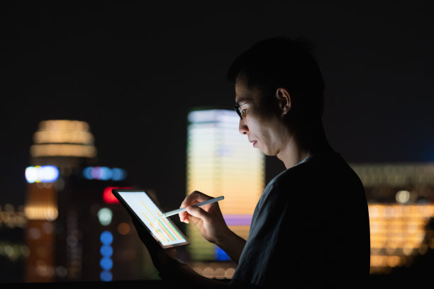 男子在城市灯光背景上使用平板电脑图片下载