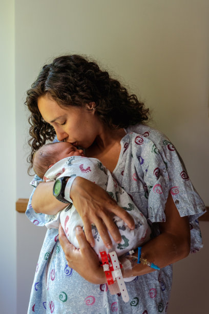 可爱的新妈妈正在亲吻她的新生儿图片下载