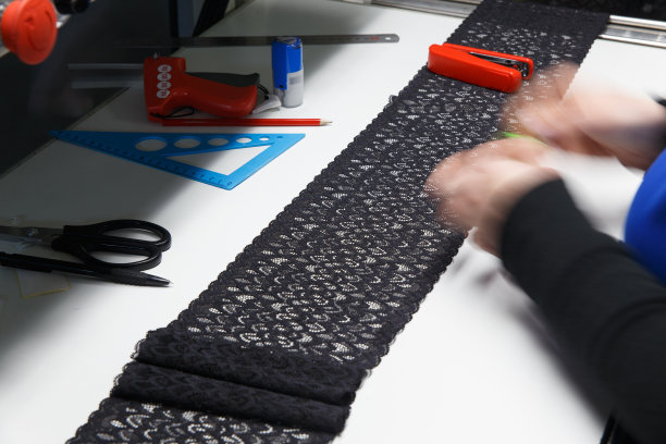 一名女员工对蕾丝缎带进行视觉质量控制图片下载