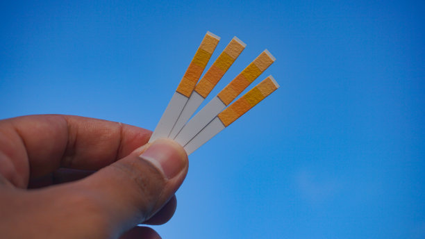 石蕊试纸放在蓝色背景的手上。具有酸性测试的通用酸碱度指示纸-选择性焦点图片下载