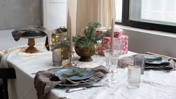 餐厅内部的圣诞装饰。用杉树树枝、玻璃杯、蜡烛和礼品盒为圣诞晚餐准备的餐桌。厨房和餐厅内部的乡村风格。图片下载