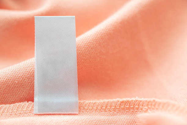 空白白色洗衣护理衣服标签上的粉红色织物质地的背景图片下载