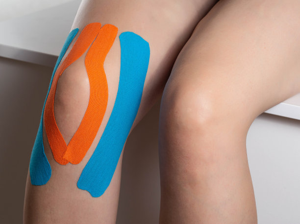 用蓝色和橙色的运动胶带固定膝关节，特写。拍摄运动中的肌肉和韧带，特写图片下载