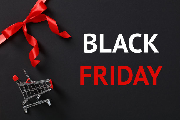 黑色星期五销售概念与红色丝带蝴蝶结在角落和购物车在黑暗的背景。图片下载