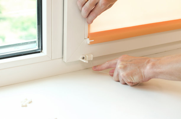 安装卷帘。男性用手近距离在窗户上安装百叶窗。图片下载