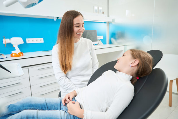 友好的儿科医生对躺在牙科椅上的孩子微笑图片下载