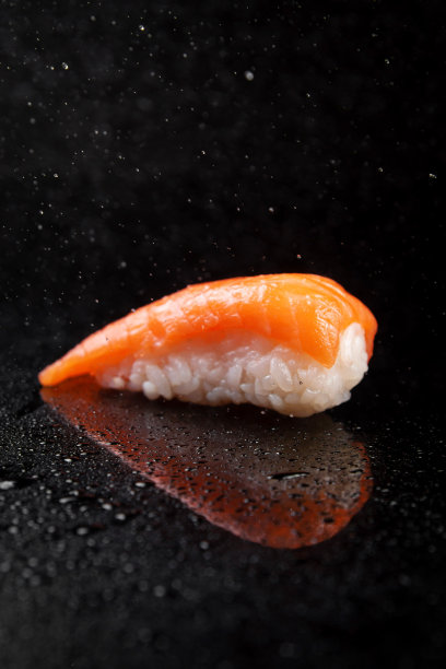寿司配米饭和三文鱼，黑色背景上有倒影和水的飞溅图片下载