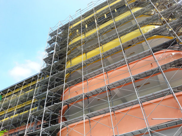搭建的房子。学校。建筑。高层建筑,改造。用旧的屋顶和地面材料搭建脚手架。正在施工的建筑物上盖着脚手架。地面的角度图片下载