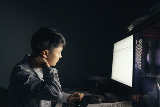 一名亚洲男子晚上在电脑前加班，感到脖子和脖子疼痛——这是不健康的生活方式图片下载