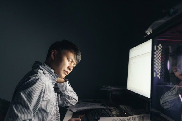 一名亚洲男子晚上在电脑前加班，感到脖子和脖子疼痛——这是不健康的生活方式图片下载