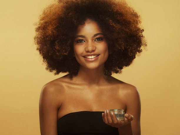 年轻美丽的黑人女性拥有完美的皮肤和爆炸头发型，手持化妆罐面霜图片下载