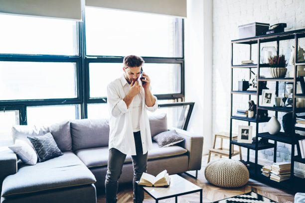 困惑的男性自由职业者在公寓打电话图片下载