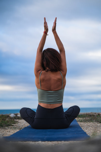 背面的妇女表演瑜伽姿势在自然环境下的大海。图片下载