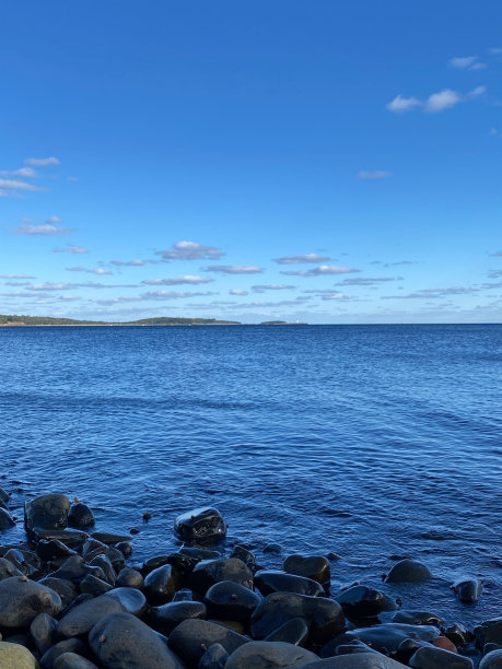 海滩上的黑色岩石和地平线上山脉的美丽海景的垂直照片图片下载