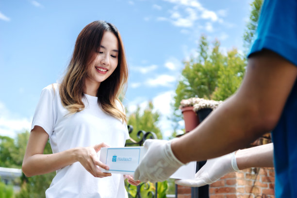 送药员带着口罩和手套的快递员在预防冠状病毒期间购买医用药丸，安全居家和隔离理念，志愿者带着捐赠物品。图片下载