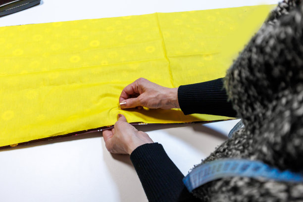 一位女裁缝正在车间里用针准备布料。图片下载