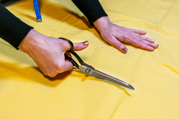 一名妇女在裁缝店用剪刀处理纺织品。图片下载