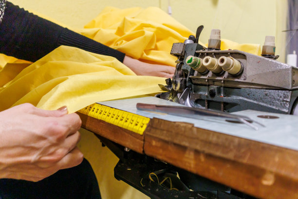 一个女裁缝正在用缝纫机缝制衣服的特写照片。图片下载