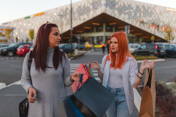 两名女性朋友在购物中心外拿着购物袋大笑的齐腰画像图片下载