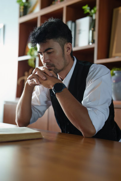 一幅英俊稳重的亚裔男子坐在桌前看书的肖像图片下载