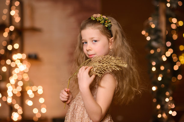 女孩穿着节日礼服，头发飘逸，肩上扛着一根金色的装饰树枝图片下载