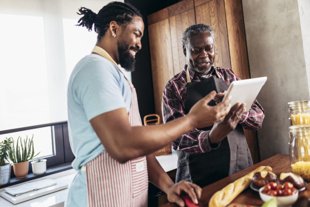 成年的儿子和年长的父亲在厨房做饭。图片下载