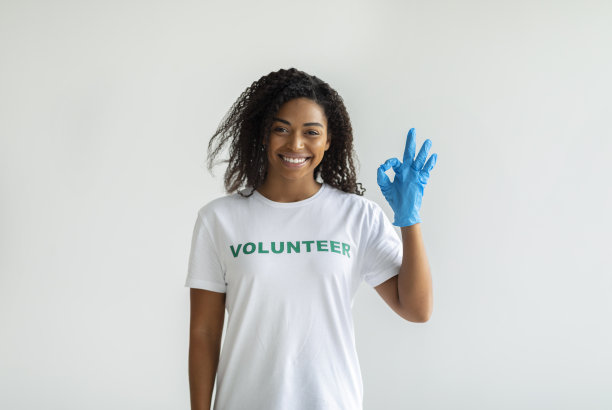 慈善优雅的概念。快乐的女志愿者戴着手套，对着镜头，对着墙微笑，做着OK的手势图片下载