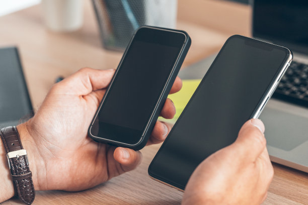 男子使用移动智能手机。商务人士在办公桌前使用手机。图片下载