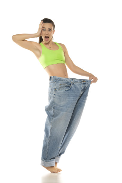 饮食观念与减肥。快乐的惊奇女人在白色背景的超大牛仔裤图片下载