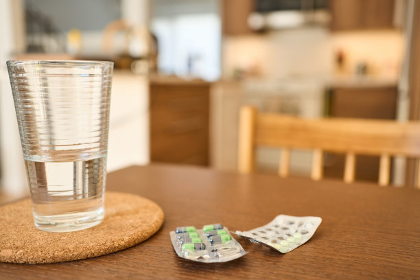 桌上放着两个药箔包和一杯水图片下载