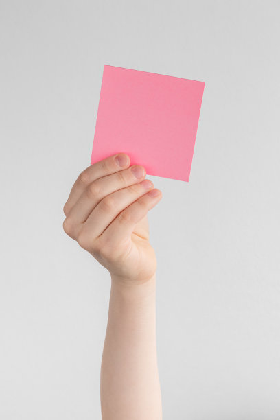 孩子手里拿着一个方形的粉色空白提醒或纸笔记，上面有白色和灰色的背景，复制空间图片下载