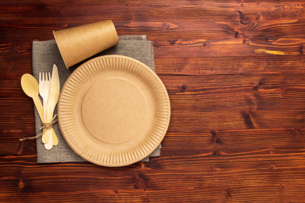 纸杯、盘子和木制餐具放在木制背景上。生态工艺纸餐具。零浪费，环保理念。本空间图片下载