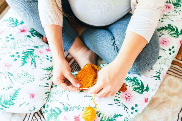 孕妇编织婴儿冬衣。怀孕的母亲钩针孩子布。可爱的孕妇编织时尚的冬季女婴衣服。温暖的冬季舒适的衣服给宝宝。图片下载