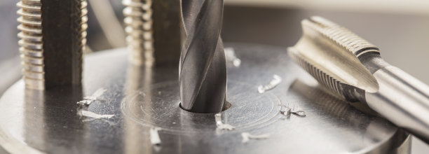 金属钻头在工业钻床上用刨花在铝坯上钻孔。金属加工行业。多种刀具和立铣刀。图片下载