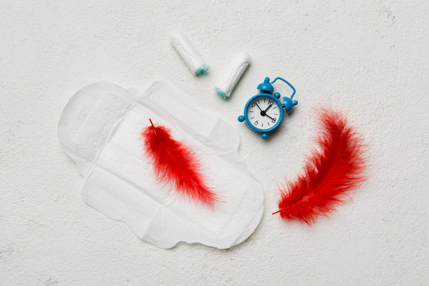 配有女性卫生棉条和月经卫生巾的响铃闹钟。妇女危险期与月经的医学概念。女性日常卫生。本空间图片下载