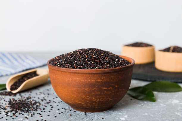 在碗和勺子里的藜麦种子在彩色背景上。健康的kinwa在小碗里。健康的超级食物图片下载