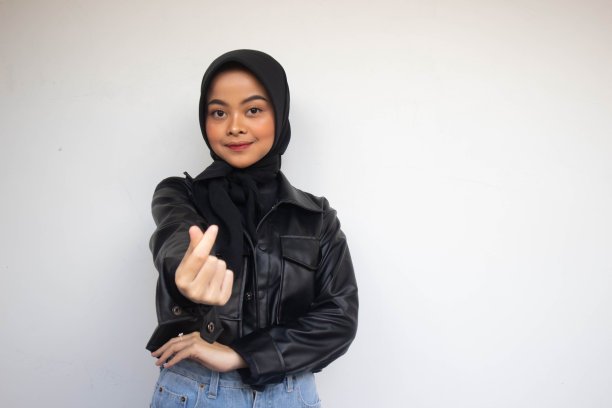 亚洲美丽微笑的头巾女孩显示爱韩国标志与模糊的背景孤立的白色背景手指。印尼妇女图片下载