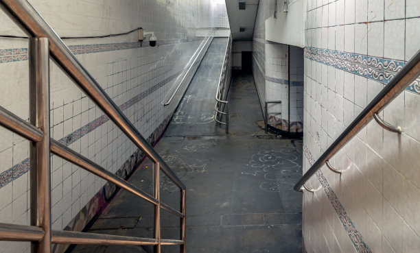 楼梯通向内部的公共地下通道，有白色瓷砖墙和闭路电视。图片下载