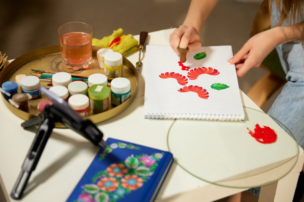 产品的绘画手法。艺术家在家纸上画花卉图案、装饰物的特写。博主拍摄在线课程。爱好和休闲观念。图片下载