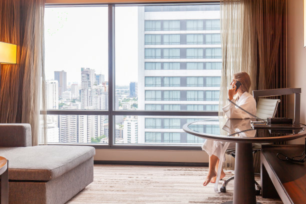 穿着浴袍的女人坐在现代化的酒店，公寓，打电话图片下载
