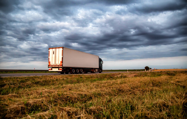 一辆装有半挂车冰箱的现代卡车在乌云密布的天空下运输着货物。由道路运输组织进行的运输，货物周转，进口替代图片下载