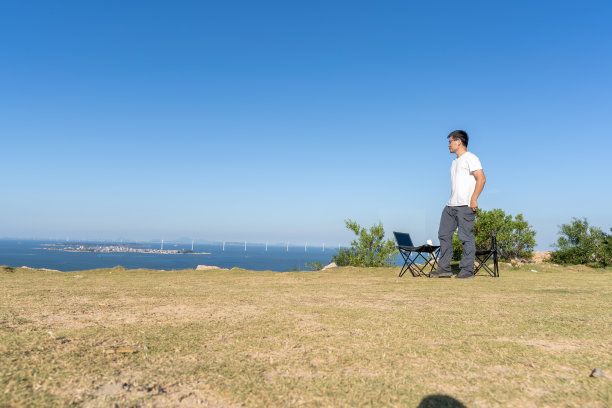 一个亚洲人走在海边的田野里图片下载