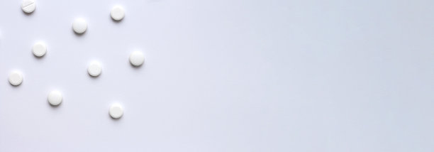 医学背景，白色背景上的药丸。带有复制空间的医药药学和医药概念。横向横幅上的医疗主题与空间的文字。散落的白色药丸图片下载