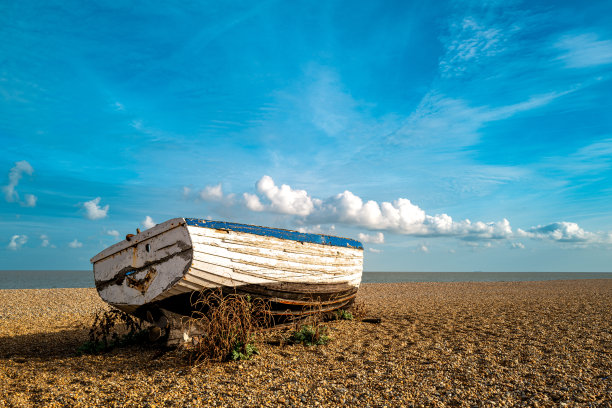在萨福克石滩上看到的一艘严重风化的木制渔船的孤立视图。图片下载