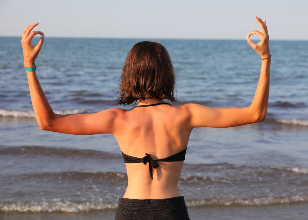 苗条的女孩背靠背做瑜伽冥想练习和做OM符号图片下载