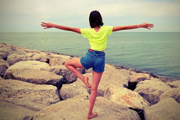 女孩在岩石上做体操，具有古色古香的效果图片下载