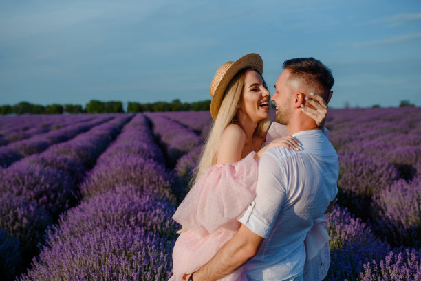 一个穿粉红色衣服和帽子的女人和一个穿白色衬衫的男人走在一片淡紫色的田野里。图片下载