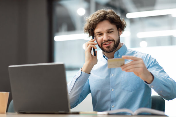 微笑的男子使用信用卡在智能手机上通话图片下载