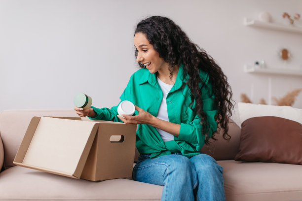 兴奋的女性拿着护肤品在家里打开纸箱图片下载